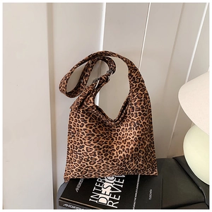 Detail of leopard print hobo bag in suede fabric placed on a black design book