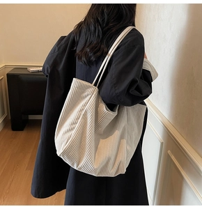 Grand sac fourre-tout en velours côtelé beige porté à l'épaule pour montrer le volume