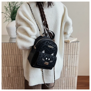 Detailed close-up of leopard print backpack with cat-shaped pocket and golden chain straps