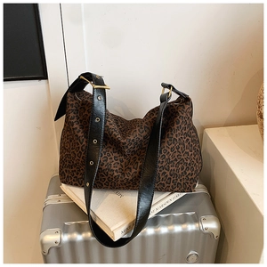 Detail of leopard print tote bag featuring black leather strap and gold metal hardware