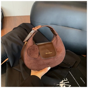 Detail of dark brown suede hobo bag with gold logo and heart charm accessory