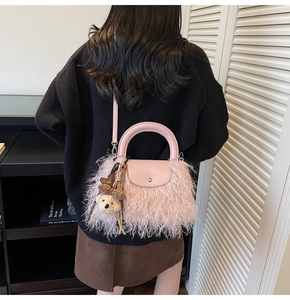 Detalle de bolso rosa de peluche con solapa de cuero y colgante de osito tierno