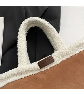 Close-up of suede bucket bag with white faux shearling handle and clearok logo detail