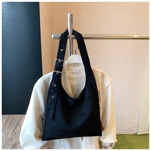 Detail view of black tote bag with wide adjustable shoulder strap and metal buckle