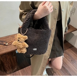 Detail of coffee brown fuzzy tote bag featuring plush bear charm and soft lamb wool texture