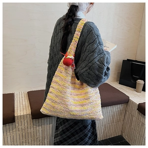 Close-up of rainbow chunky knit tote bag with a red crochet fruit charm accessory