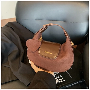 Close-up of brown suede half-moon handbag with leather flap and heart-shaped pendant