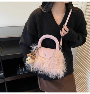 Bolso rosa de peluche con asas redondas y colgante de oso en una toma de detalle lifestyle