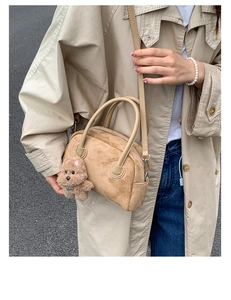 Detail of vintage suede Boston bowling bag with cute plush bear charm in outdoor setting