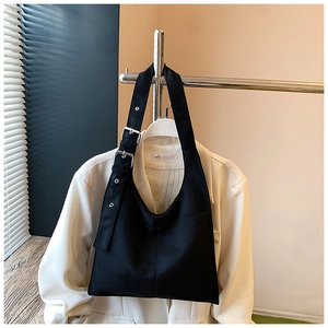 Detailed view of black suede bucket bag with adjustable silver buckle on a blazer