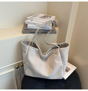 Sac cabas minimaliste en velours côtelé gris clair posé sur un tabouret de style moderne