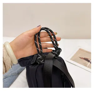 Detail of black backpack featuring a durable black and white braided rope top handle
