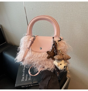 Detalle de bolso de felpa rosa con asa de cuero y bonitos colgantes decorativos