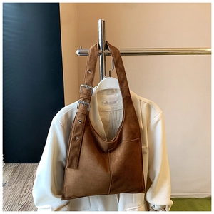 Detail of caramel suede hobo bag featuring silver adjustable buckles on the shoulder strap