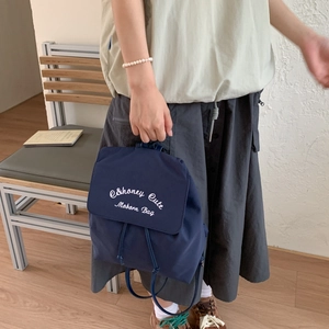 Detail of navy blue nylon backpack with Honey Cute embroidery in a cozy lifestyle setting