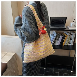 Detail view of colorful woven tote bag with crochet strawberry and lucky charm pendant