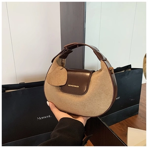 Detail of retro half-moon handbag featuring dark brown leather and khaki suede textures