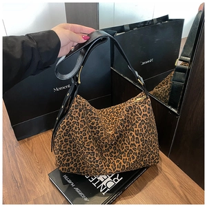 Detail of leopard print hobo tote bag featuring wide black strap and gold metal zipper