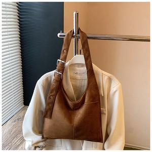 Close-up of brown suede hobo bag featuring adjustable strap and silver metal eyelets