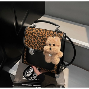Detail view of leopard print crossbody bag with silver twist lock and puppy pendant