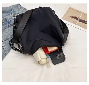 Spacious interior of black nylon crossbody bag showing umbrella, phone, and power bank