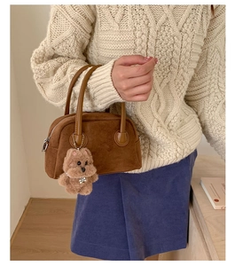 Close-up of brown suede bowling bag featuring a cute plush dog charm with metal tag