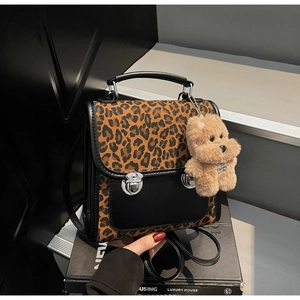 Détail du sac à main imprimé léopard avec poche en cuir et breloque chien en peluche