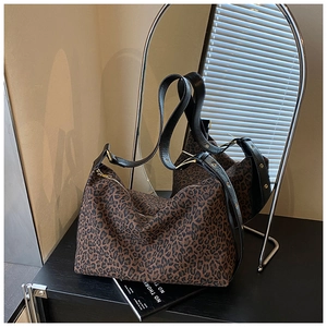 Detail of leopard print canvas hobo bag with black leather strap and gold hardware accents