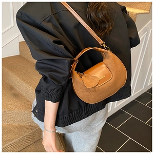 Detailed view of brown matte leather crescent bag with heart charm and brand logo