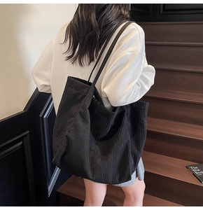 Gros plan sur la texture du sac cabas en velours côtelé noir et ses doubles anses
