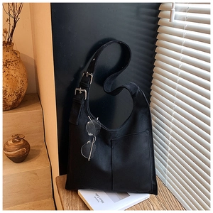 Detail of suede crescent bucket bag with adjustable buckle strap and outer pocket