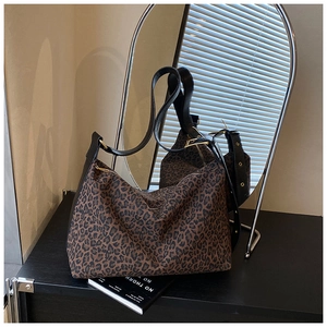 Leopard print canvas tote bag with black leather strap and gold buckle detail
