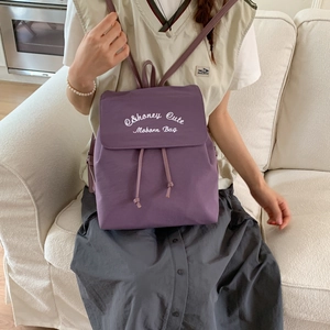Detail of lavender nylon backpack featuring white embroidery and drawstring closure