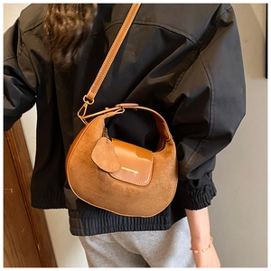 Detail of brown matte leather half-moon crossbody bag shown on model with metal hooks
