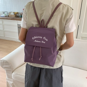 Detail of purple backpack featuring Honey Cute Modern Bag embroidery and drawstring