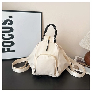 Detail of cream canvas mini backpack featuring black and white woven rope handle