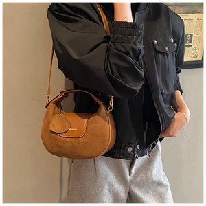 Detail of a brown suede and smooth leather patchwork hobo bag with a gold logo