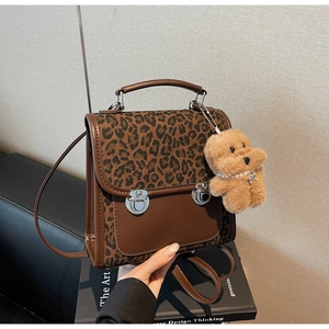 Détail du sac léopard avec boucles métalliques et charm d'ours en peluche doux