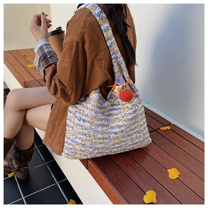 Detail of colorful woven tote bag with texture and handmade strawberry charm pendant
