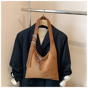 Detail of brown suede hobo bag featuring silver adjustable buckle and front pocket