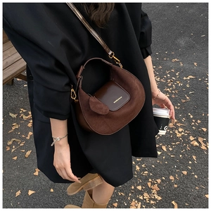 Detail view of coffee-colored frosted suede crescent bag with gold-tone hardware and charm