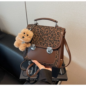Detail of vintage leopard print backpack featuring silver double buckles and plush dog charm