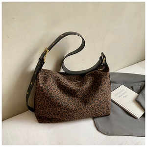 Detail of leopard print tote bag featuring a wide leather strap with gold adjustable buckle