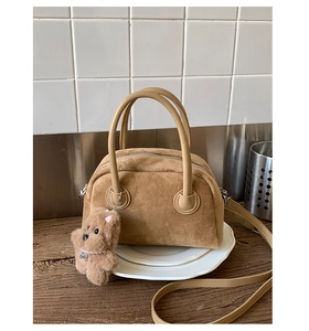 Detailed macro of brown suede bowling bag featuring a cute plush bear pendant accessory