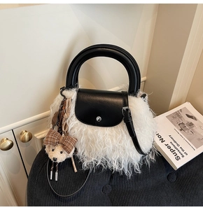 Detalle del bolso de piel sintética blanca con solapa de cuero negro y colgante de oso