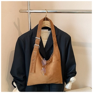 Detail of caramel suede bucket bag with adjustable shoulder strap and front pocket