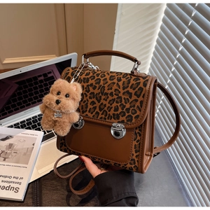 Détail d'un sac bandoulière léopard avec boucle argentée et charm chien en peluche
