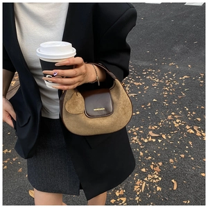 Detail view of camel suede and brown leather hobo bag with gold logo on a textured finish