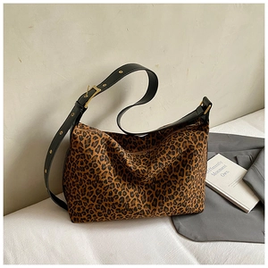 Macro shot of large leopard print tote bag featuring wide black leather strap and gold buckle