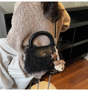 Detalle de bolso de mano de felpa negra con asa de cuero y adorno de oso lindo